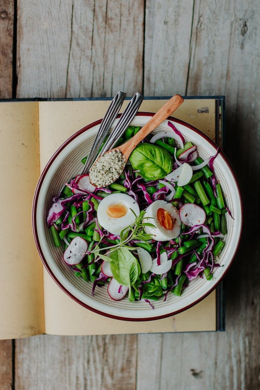 En färgstark vegansk salladsskål med blandade grönsaker, lila kål, rädisor och sparris.